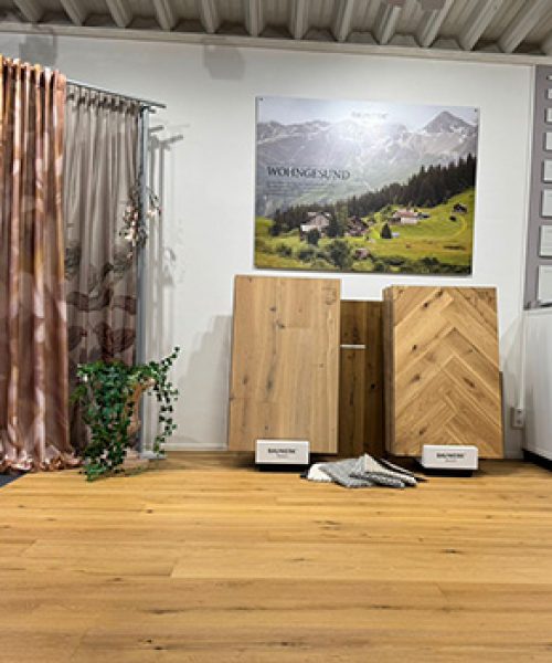 Blick ins Ladengeschäft mit Mustergardinen und großen Bodenmustern auf einem verlegten Holzboden.
