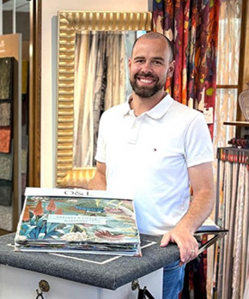 Inhaber Patrick Heckele im Laden mit an einem Tisch mit Gardinenmustern.