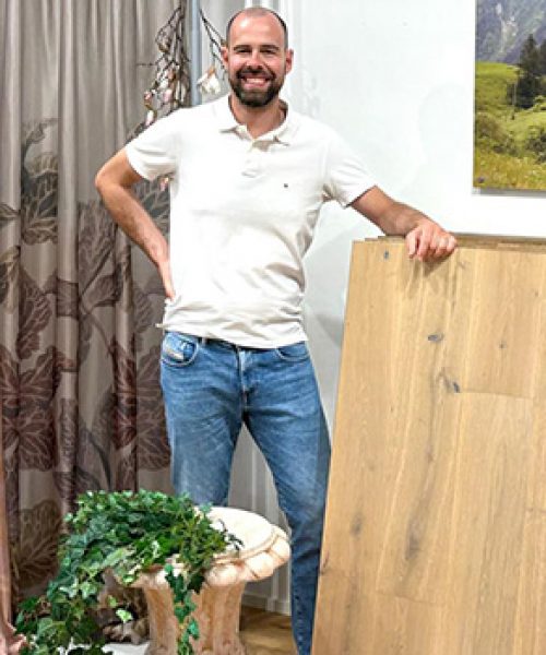 Inhaber Patrick Heckele im Laden mit großen Bodenmustern. Dahinter hängt eine Mustergardine.